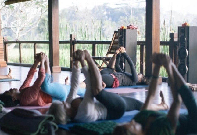 people holding their feet on floor yoga pose indoor Yoga Studios Ubud Classes Practice Bali