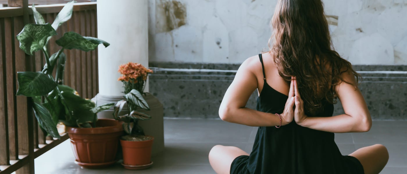 woman in prayer pose yoga plants