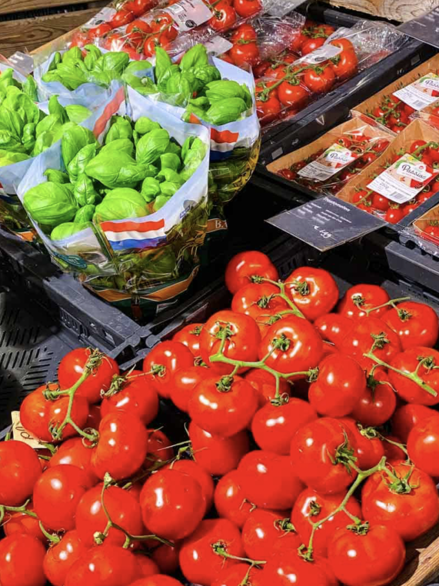 Fresh tomatoes and basil displayed in the organic produce section at Marqt Amsterdam. The image highlights the colourful, seasonal ingredients and market-style presentation associated with the store’s food-focused shopping experience.