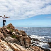 woman arms open on rock breathing facing ocean pranayama pranayam yoga breathing