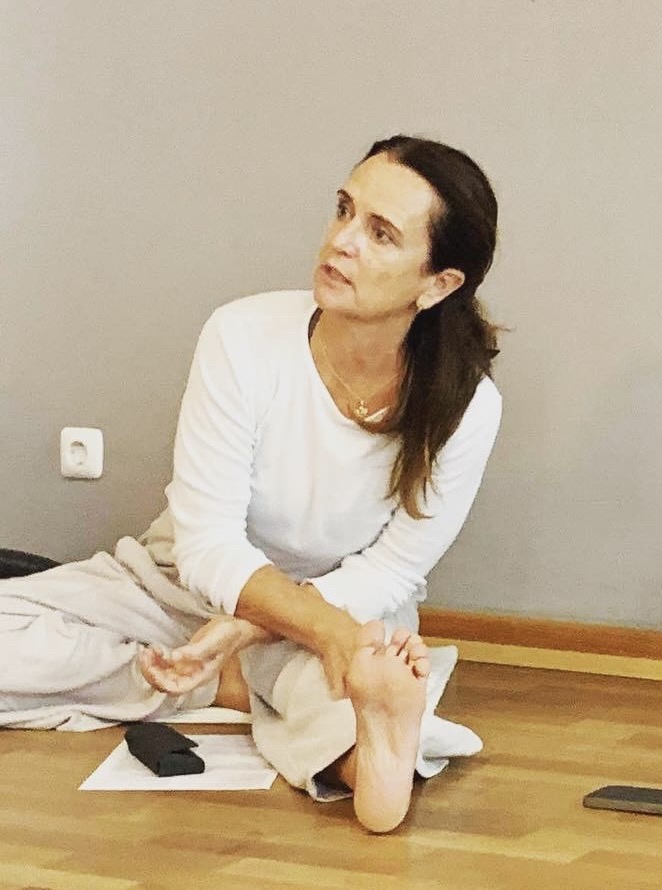 Andrea Lutz teaching a yoga class while seated, experienced Ashtanga yoga instructor