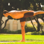 Man performing traditional Warrior 3 Pose with arms extended backward in a park