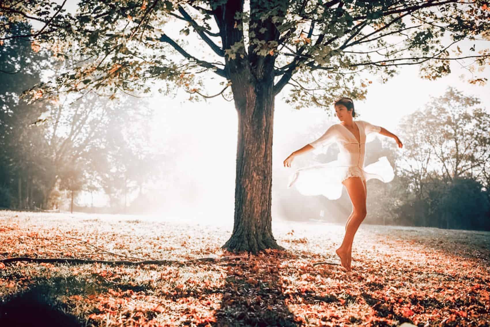 woman dancing under a tree sunset white dress leaves on floor trauma stress anxiety