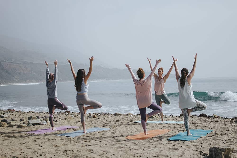 soup of people practicing yoga on the beach with mats why retreat can transform my life