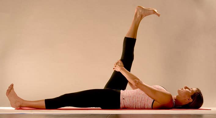 woman on floor on yoga mat supta padangusthasana (Reclined Leg Stretch) 