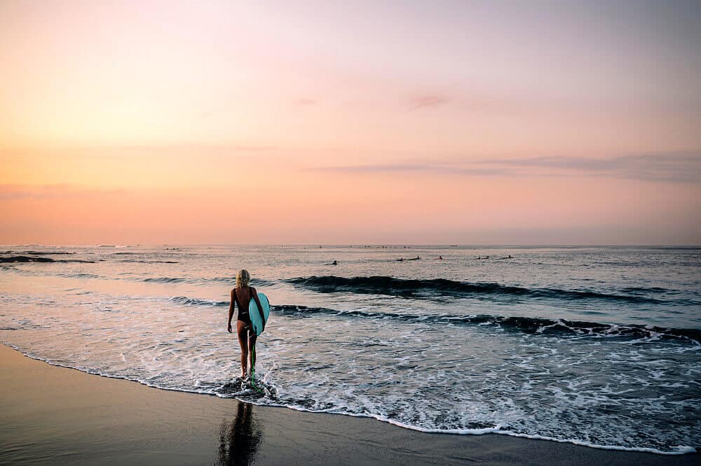 woman sunset surf board blue yoga retreat bali beach