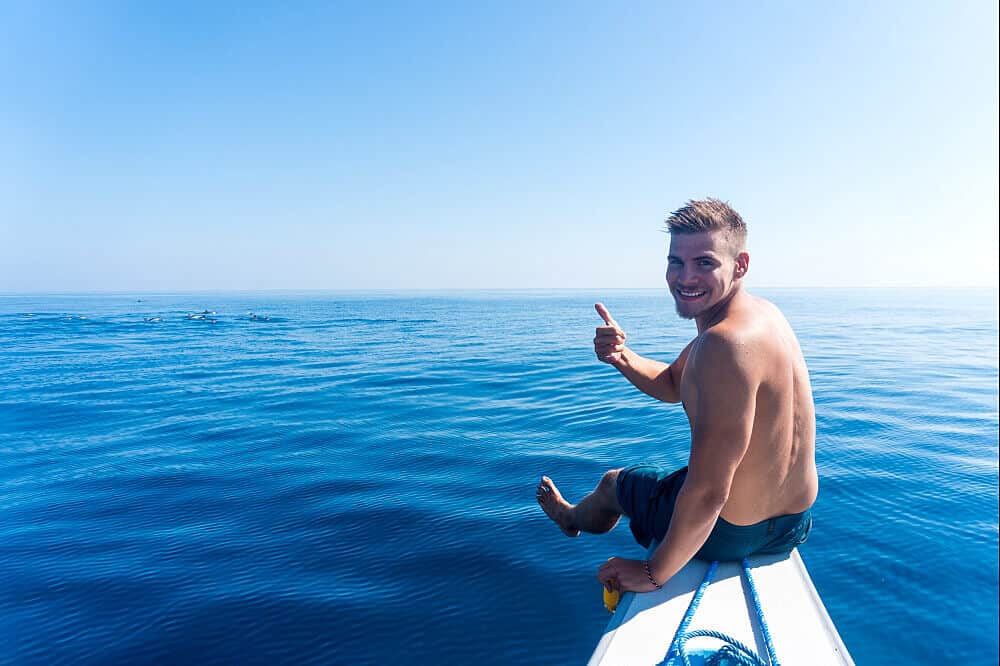 man on board thumbs up blue water lovina dolphins meditation