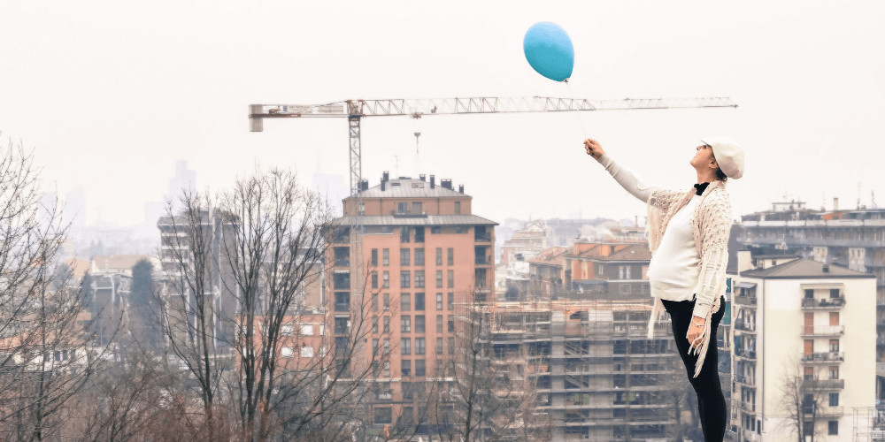 Pregnant woman with a blue balloon in the city Mother to be