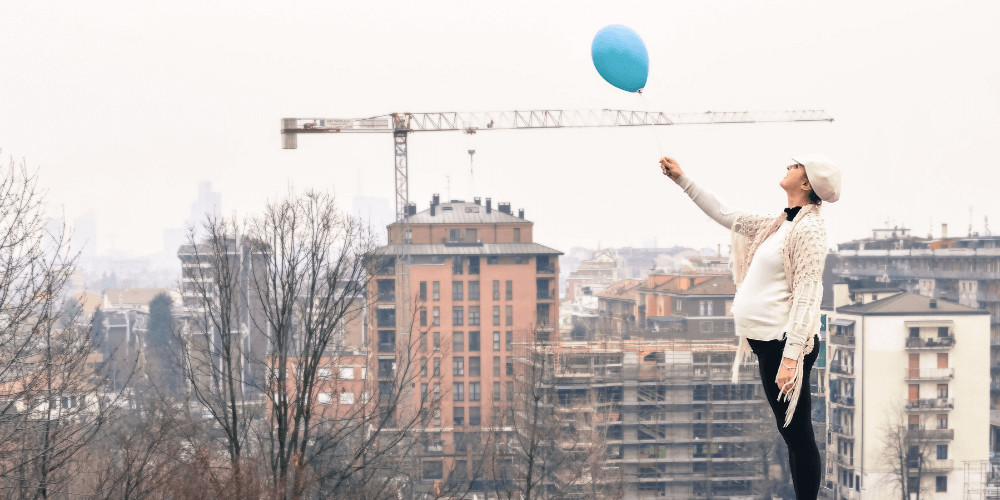 Pregnant woman with a blue balloon in the city Mother to be