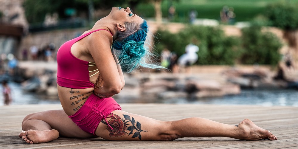 woman blue hair in a yoga pose on wooden deck outdoor red outfit