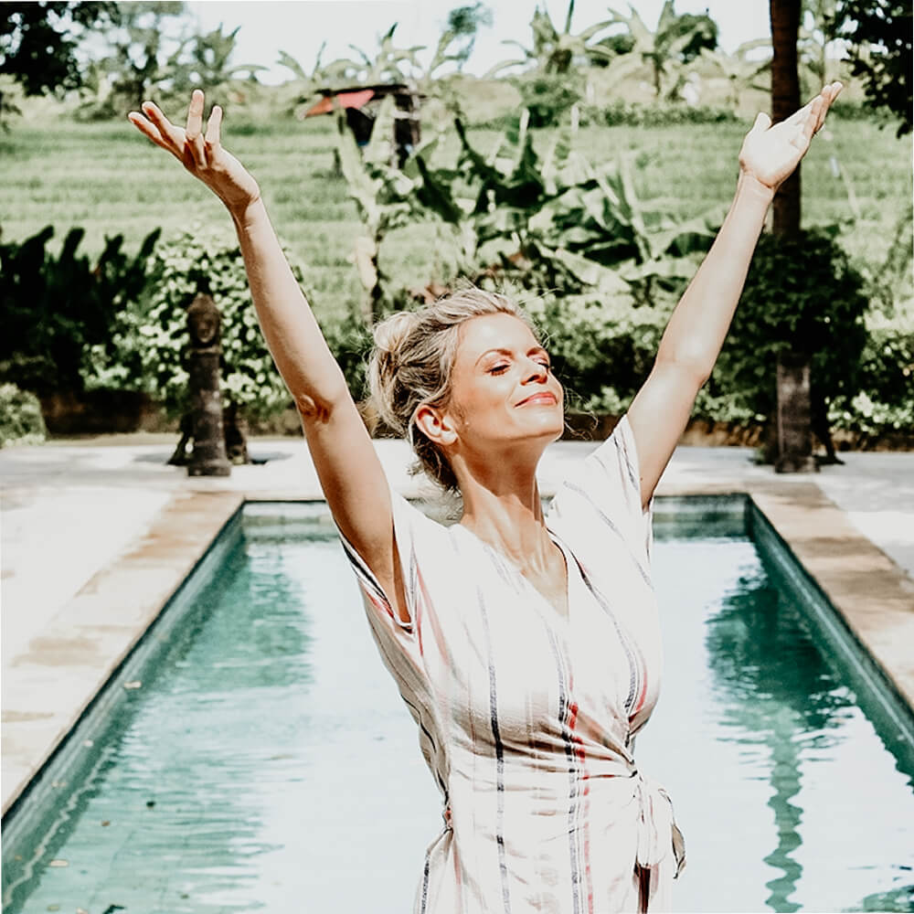 blonde woman joanna hunt raising arms up in bali feminine energy