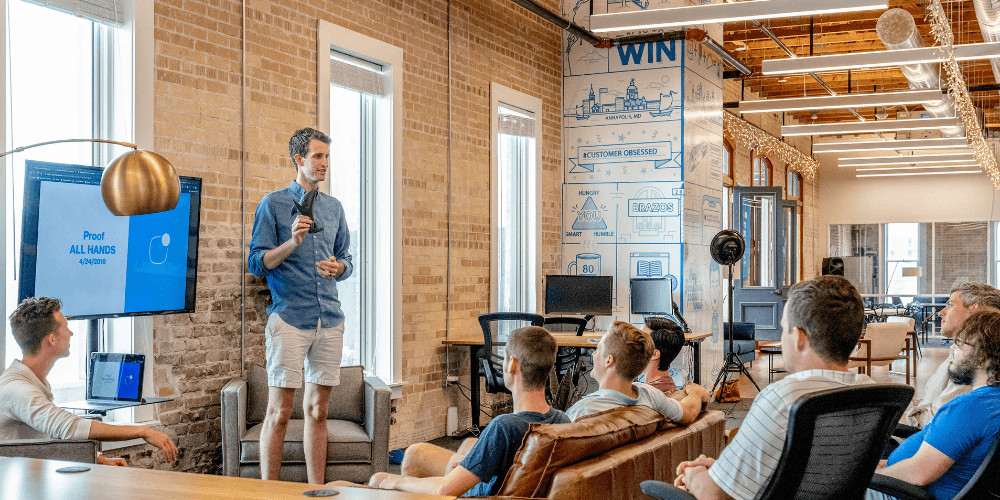 group of people meeting in office man standing microphone talking yoga studio business plans essential owner salary start open income statement costs revenue model