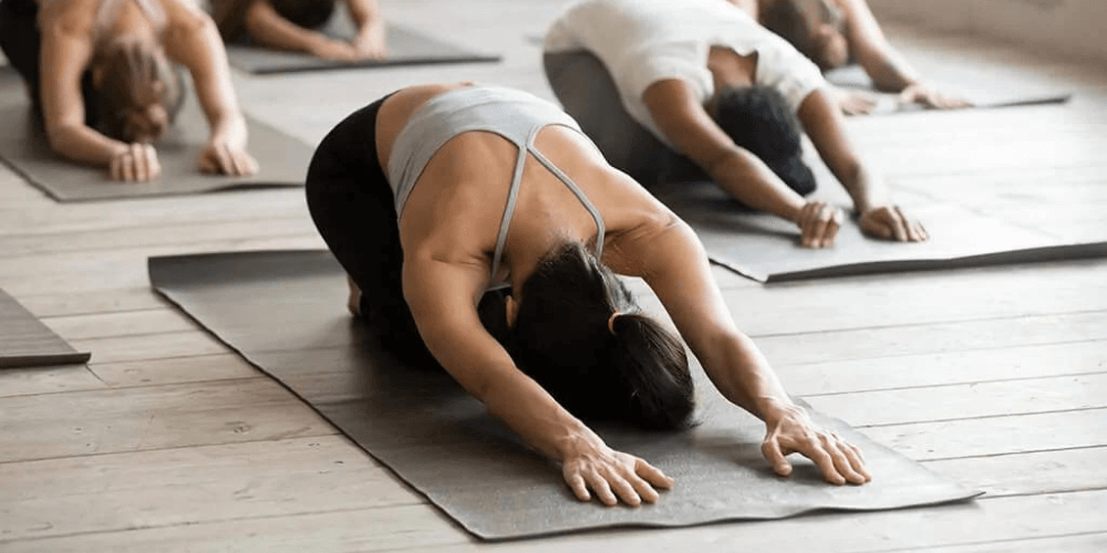 4 peaople practicing yoga in a room gate pose, side gate, parighasana, kneeling asana