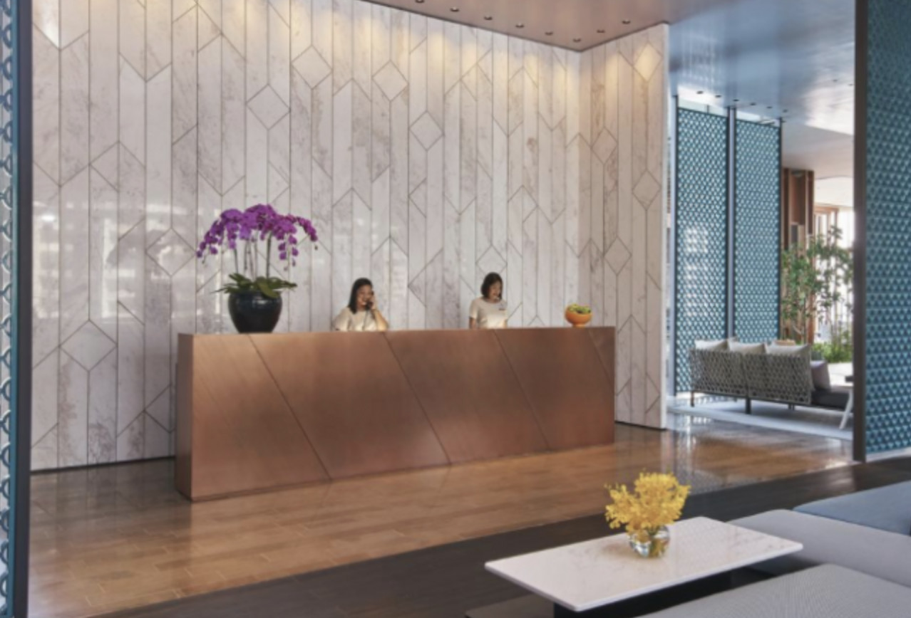 reception with wooden desk and 2 asian women green hotel Singapore