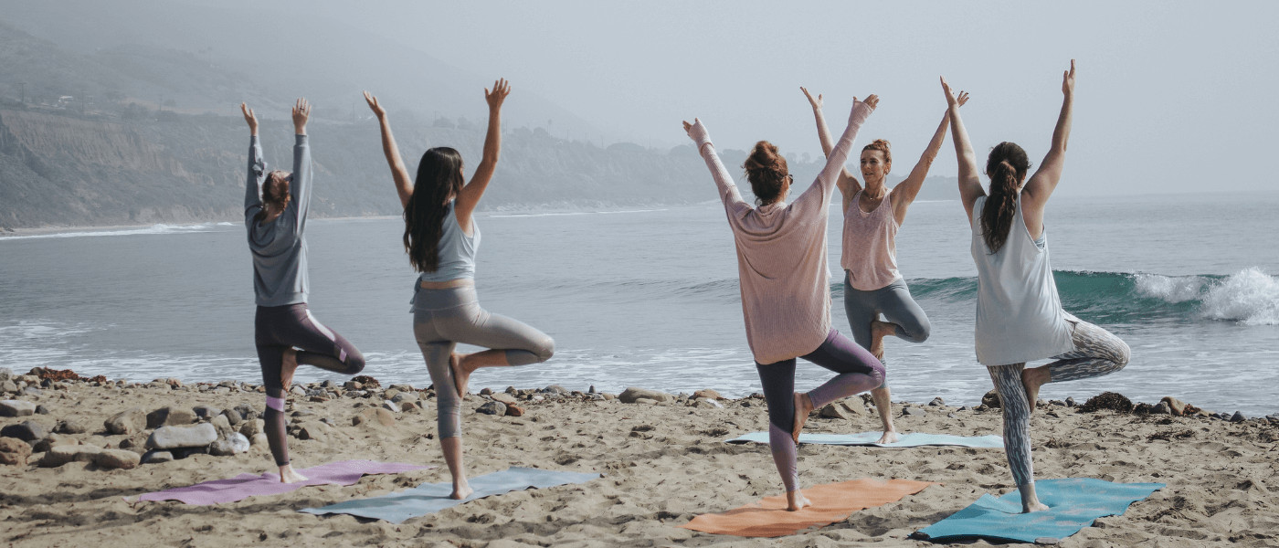 yoga group class by the beach Yoga instructor assisting studentsdoes yoga burn calories? how many calories does yoga burn yoga calories burned hot calculator