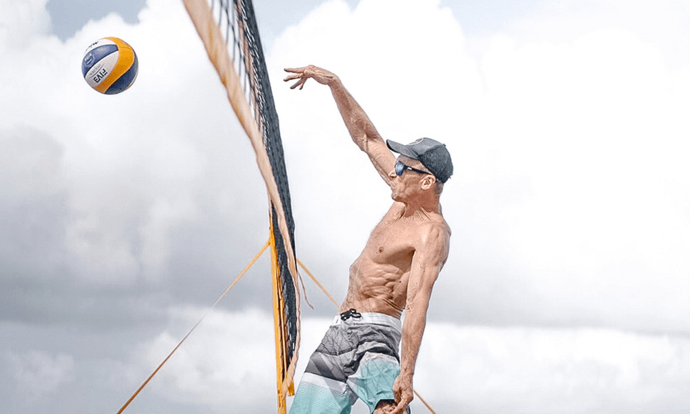 man playing with sunglasses and hat stiking  beach volleyball bali canggu kuta seminyak sanur Bali