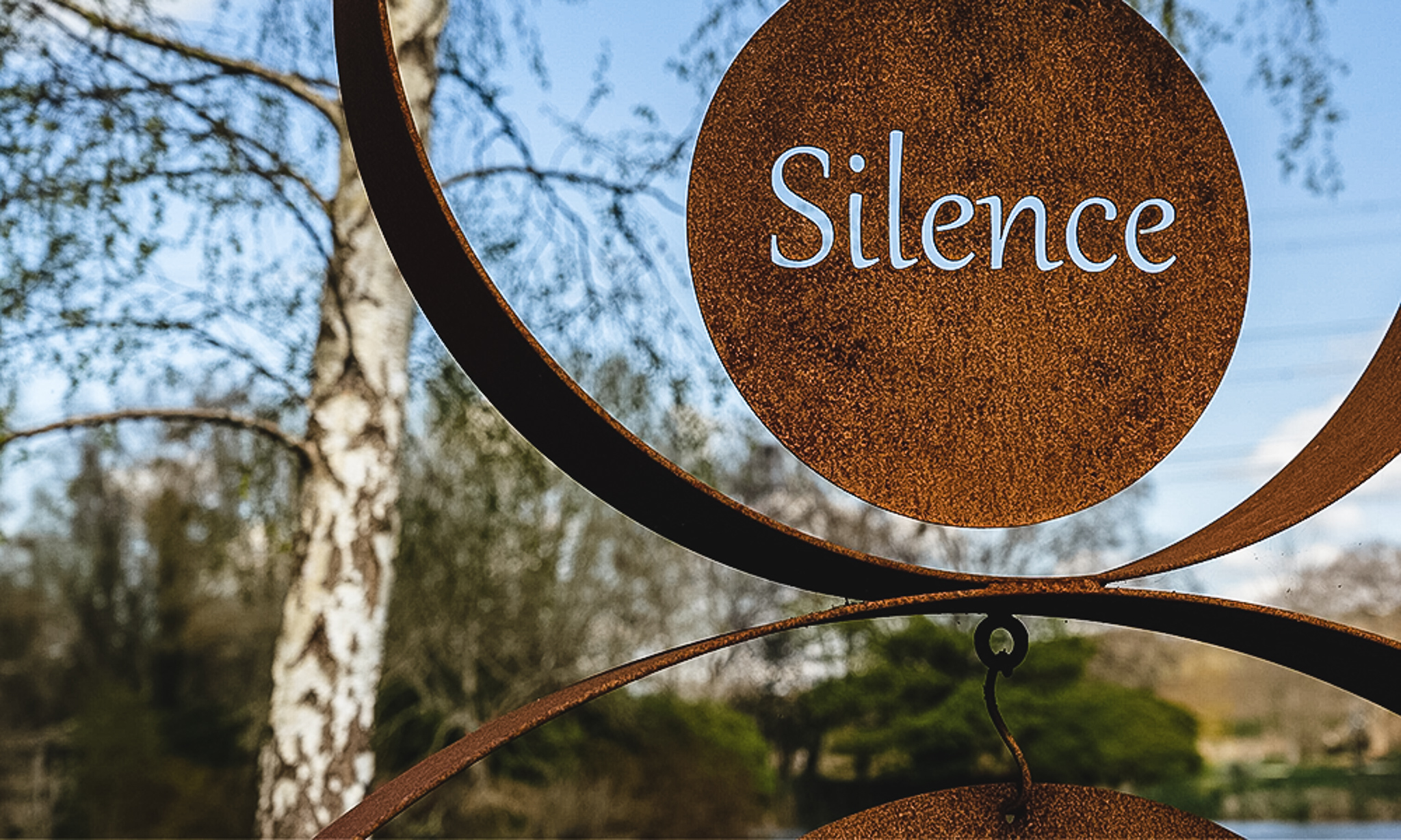 Palabra silencio en inglés escrita en escultura de metal en un bosque