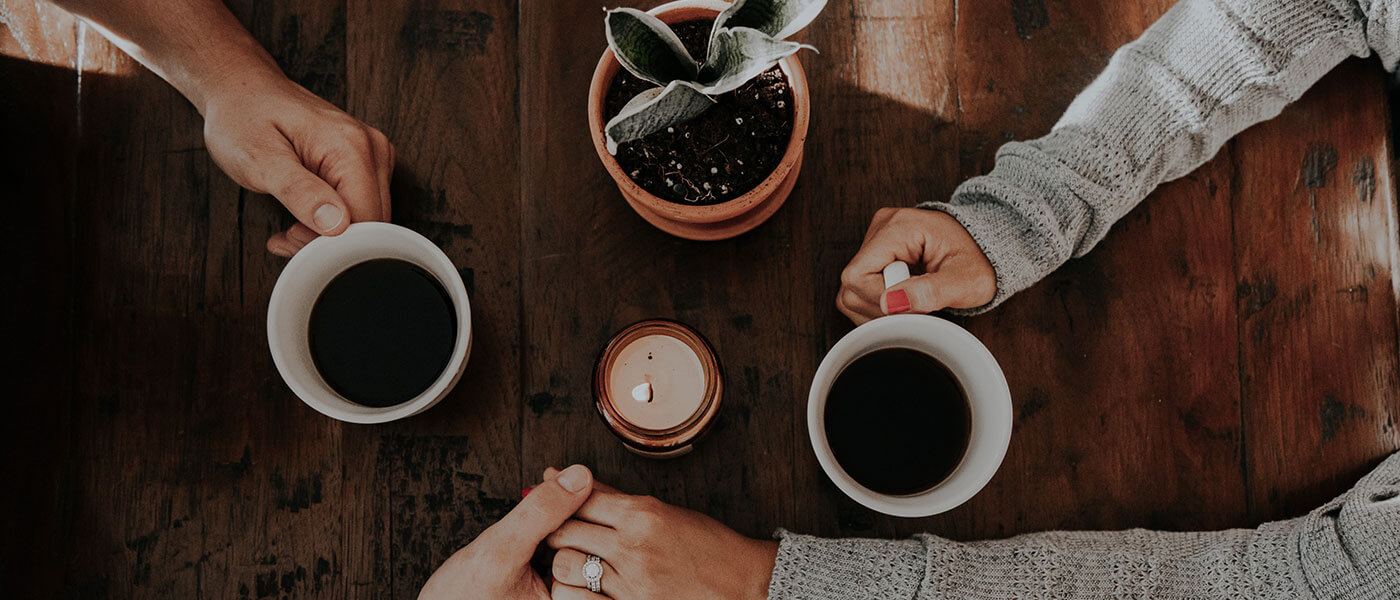 Coffe cups on table with people's arms and hands