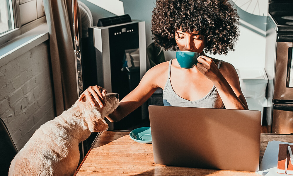 femme qui boit un the dans une tasse verte et avec son chien dan scuisine