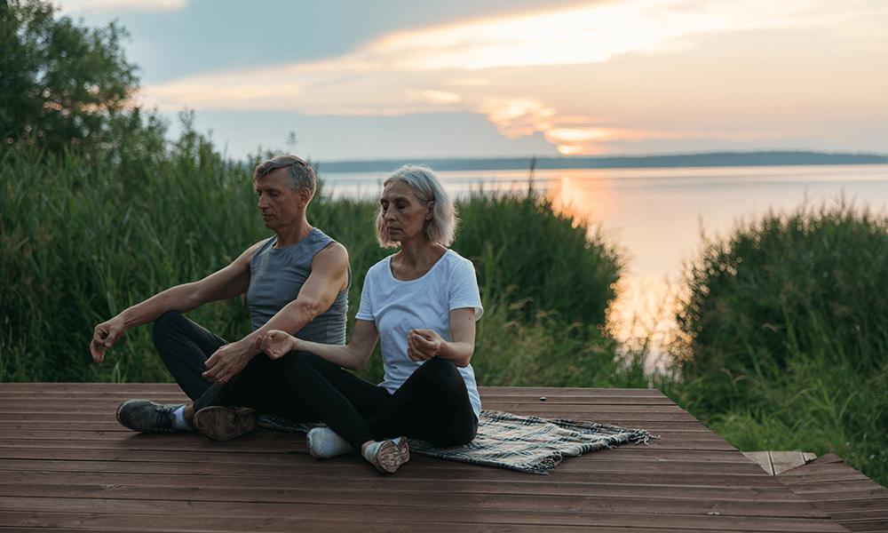 Two people meditating on a table in front of a sunset. bff 2 person yoga poses
