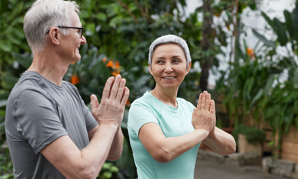 Grey haired people praying and smiling each other lovingly. bff 2 person yoga poses
