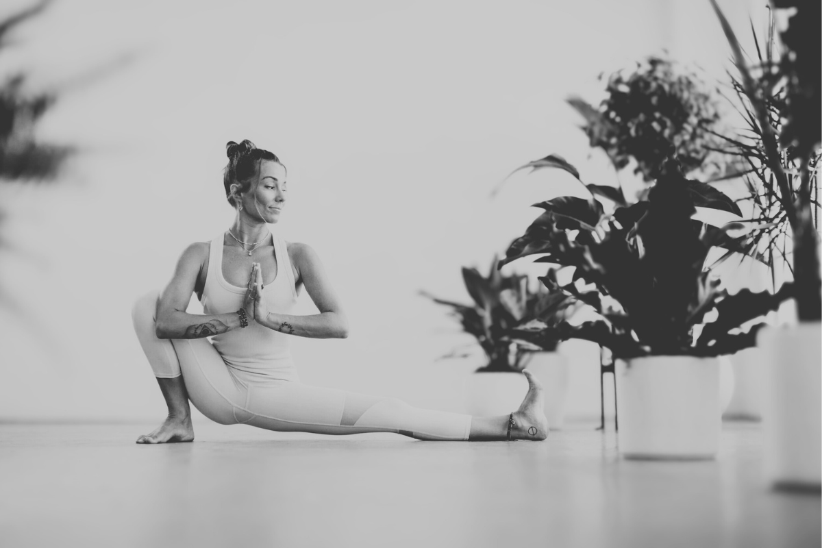 Woman practicing a deep yoga lunge twist indoors, hands in prayer position, cultivating balance and inner focus.