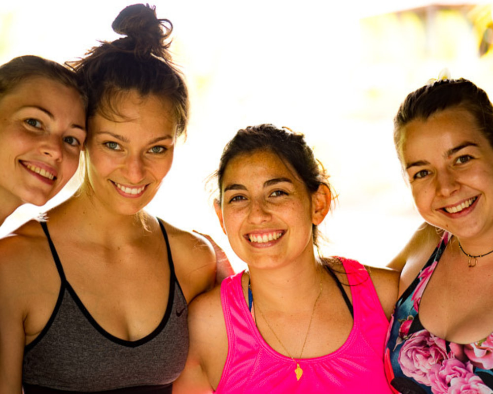 Close-up of four women with bright smiles, celebrating their yoga journey together