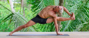 Yoga teacher Everett Nowell do yogi performing an intense asana surrounded by palm trees
