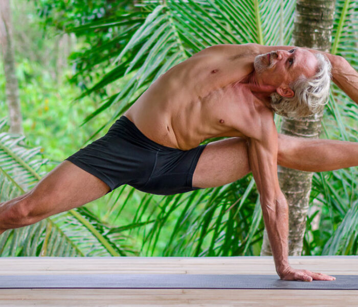 Yoga teacher Everett Nowell do yogi performing an intense asana surrounded by palm trees