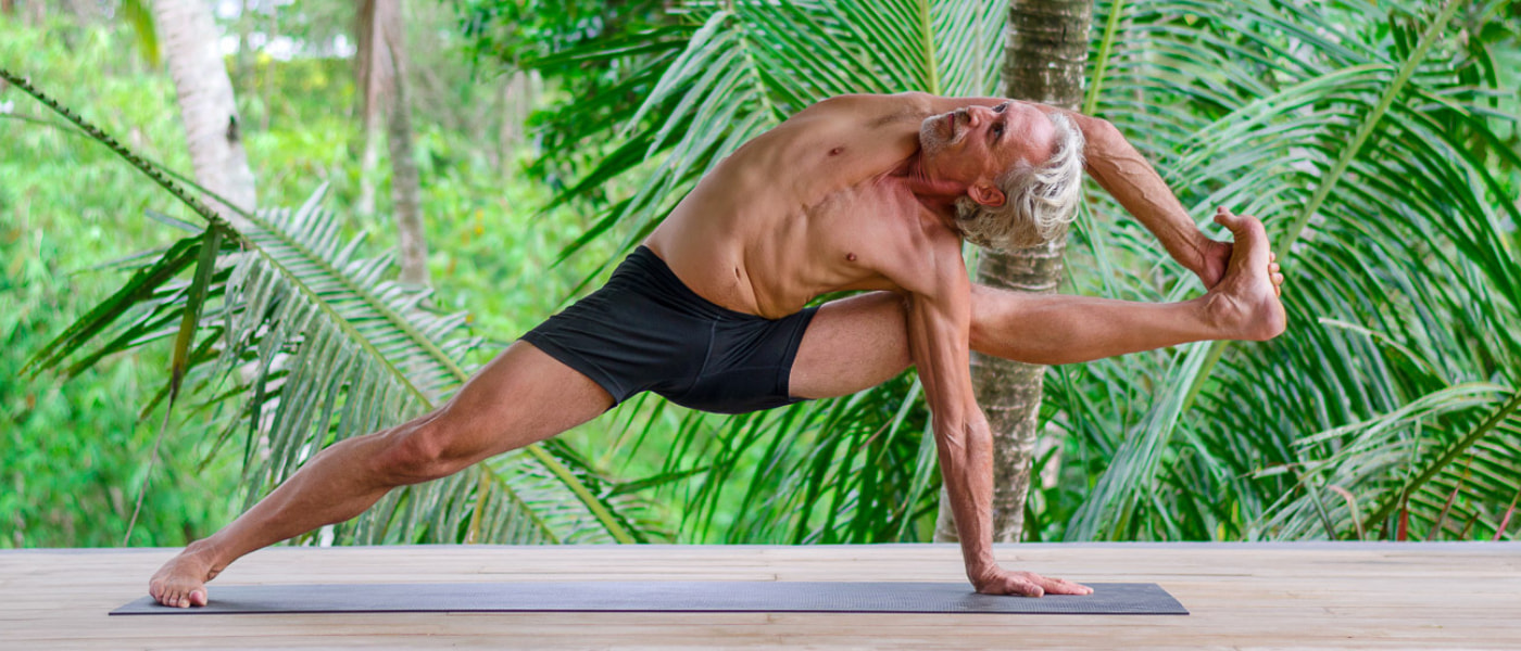 Yoga teacher Everett Nowell do yogi performing an intense asana surrounded by palm trees