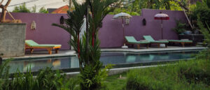 Balinese-style retreat pool with umbrellas and lush vegetation, perfect setting for rest and recovery during yoga teacher training in Bali