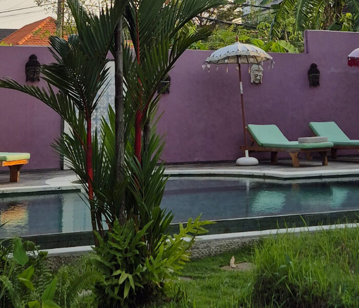 Balinese-style retreat pool with umbrellas and lush vegetation, perfect setting for rest and recovery during yoga teacher training in Bali