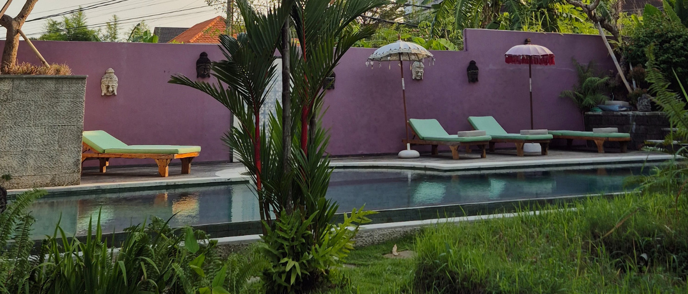 Balinese-style retreat pool with umbrellas and lush vegetation, perfect setting for rest and recovery during yoga teacher training in Bali