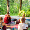 Yoga instructor leading a group session in a peaceful natural environment Outdoor yoga teacher training class in a jungle retreat setting