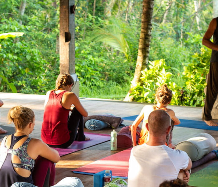 Yoga instructor leading a group session in a peaceful natural environment Outdoor yoga teacher training class in a jungle retreat setting