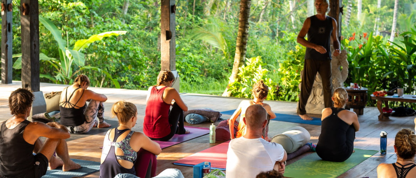 Yoga instructor leading a group session in a peaceful natural environment Outdoor yoga teacher training class in a jungle retreat setting