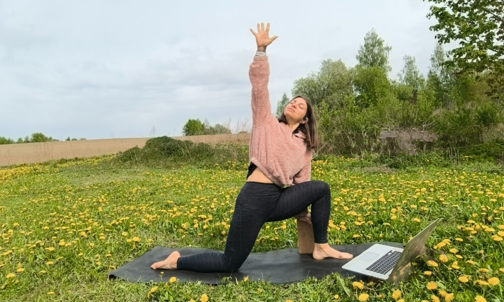 Cat Gavriusova practicing prenatal yoga outdoors in Lithuania while following the Uplifted online prenatal yoga teacher training course on a laptop.