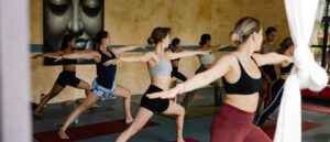 Bali yoga retreat: women in warrior pose, serene atmosphere for well-being and mental clarity
