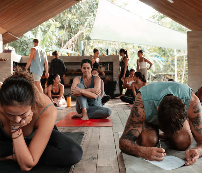 Group of yoga trainees seated on mats, writing notes during a workshop in Bali