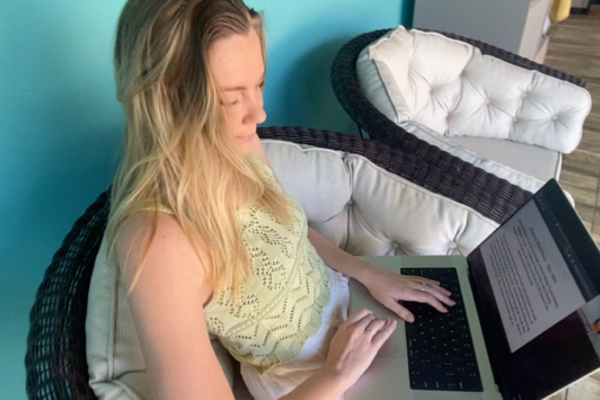 Me, working diligently on my yoga teacher training assignments, seated in a cozy wicker chair and fully immersed in my online learning journey.