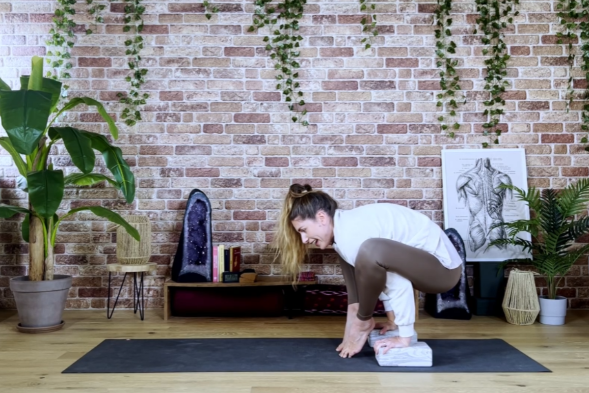 Hands pressing into yoga blocks while leaning forward into Bhujapidasana setup