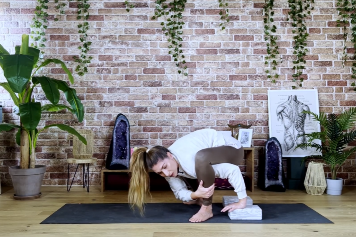 Using yoga blocks to step the leg onto the arm in Bhujapidasana preparation