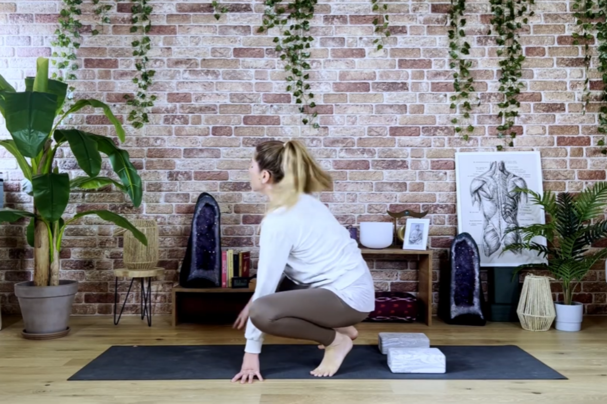 Entering Bhujapidasana from Malasana with hands reaching toward the floor