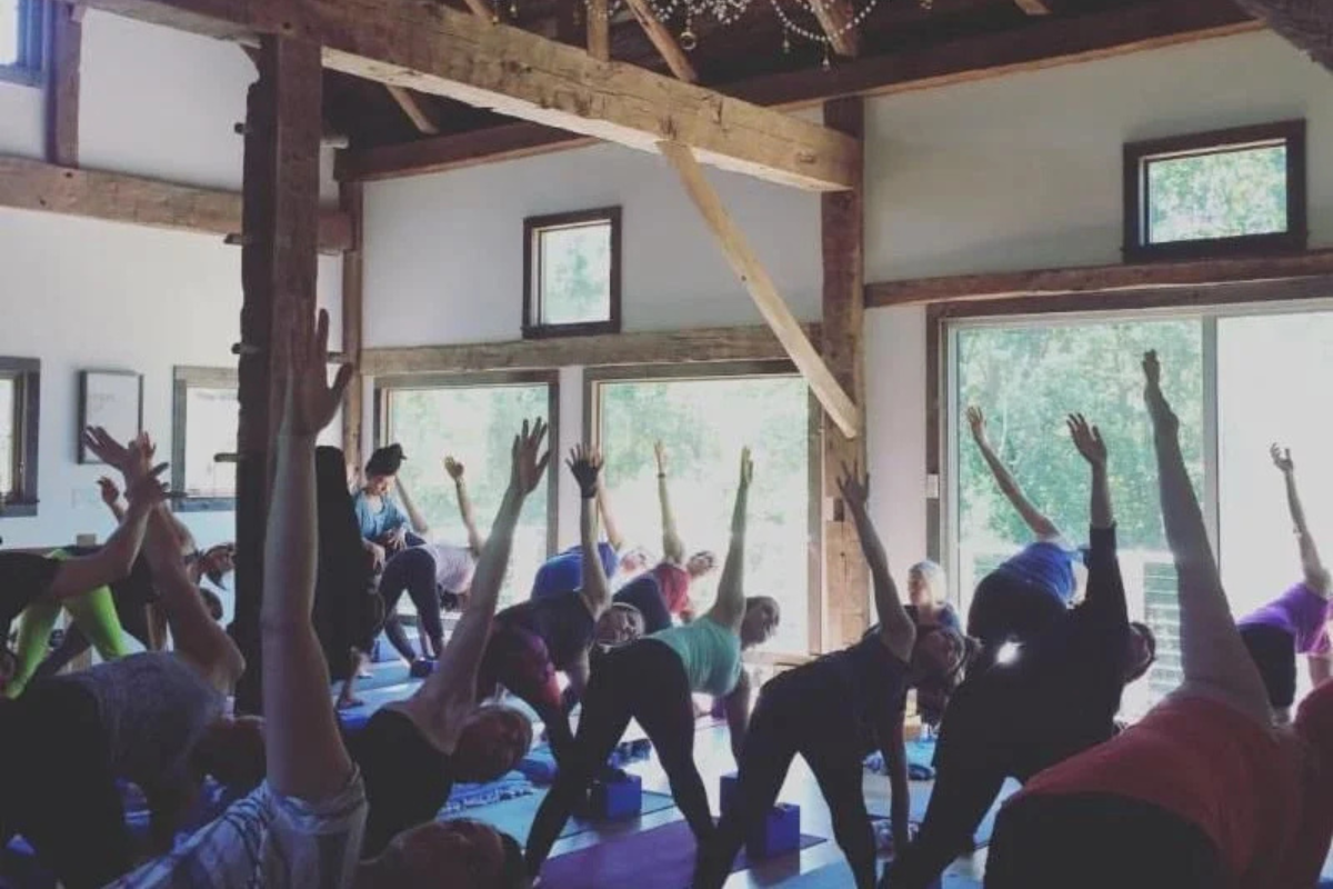Students practicing yoga together in a bright, rustic loft space at Prema Yoga Brooklyn in Prospect Park South.
