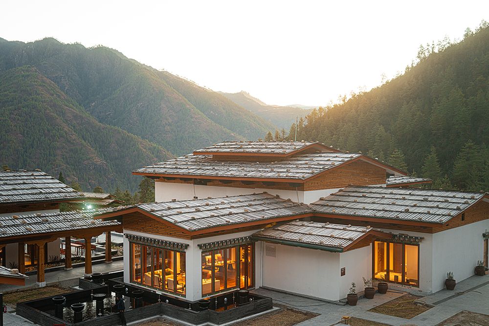 Taj Paro luxury hotel in Bhutan at sunset, set in the Paro Valley mountains.