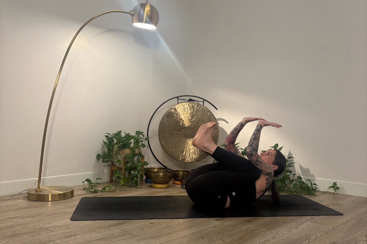 Michelle Young practicing standing forward fold on yoga mat in home studio.