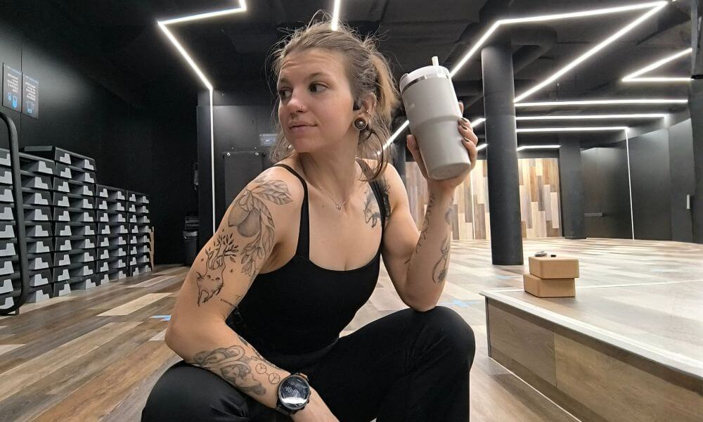 Woman in Graphene-X Kyorene Nourish Tank and Thermagraph Pants resting between workouts in a modern gym studio