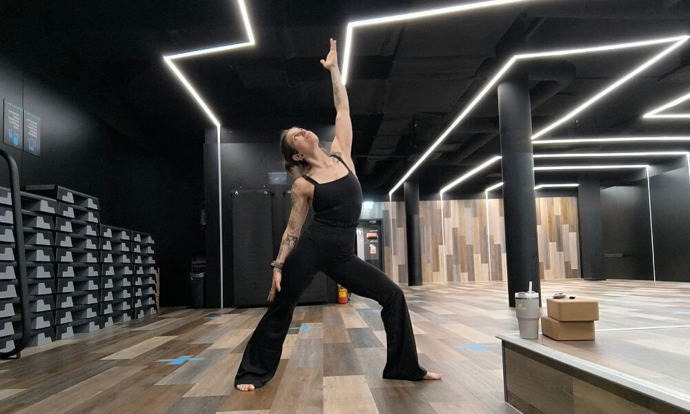 Woman wearing Graphene-X Kyorene Everywhere Jumpsuit performing a yoga pose in a modern studio during activewear test