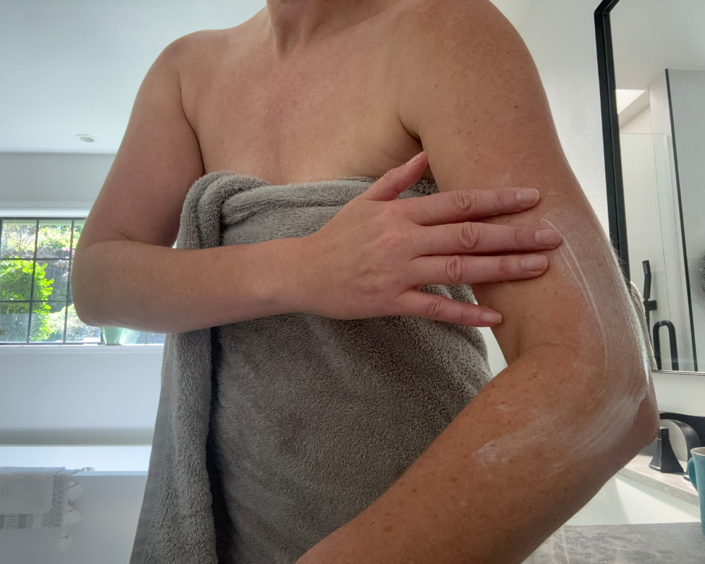 Applying OM Botanical magnesium body lotion to arm for hydration and skin nourishment