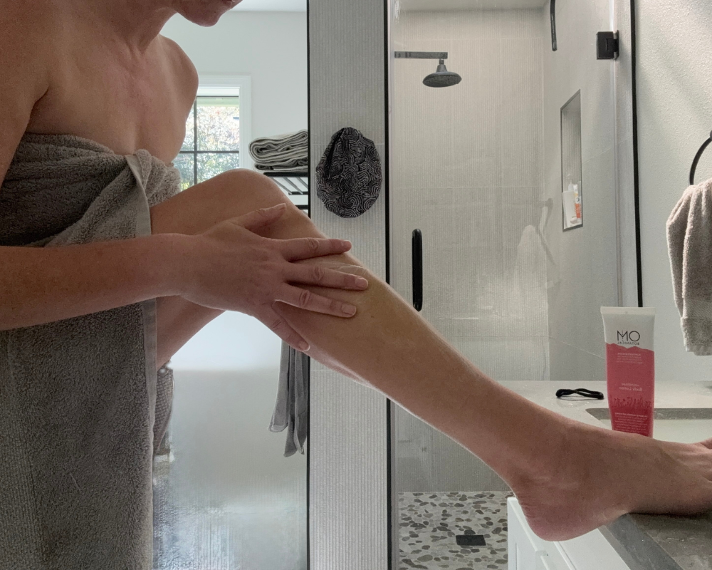 OM Botanical magnesium body lotion being applied to legs after shower for muscle recovery and hydration